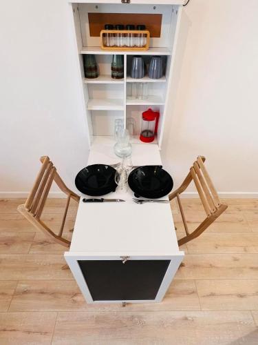 une table blanche avec deux verres et deux chaises dans l'établissement La Cachette, à La Grande Motte