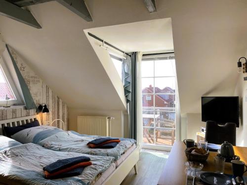 a bedroom with two beds and a tv and a window at Huus Waterkant 07 auf Amrum in Wittdün