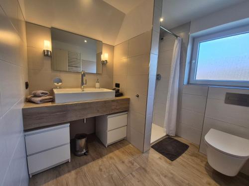 a bathroom with a sink and a toilet and a window at Ferienwohnung Leer-Stadtmitte, 15131 in Leer