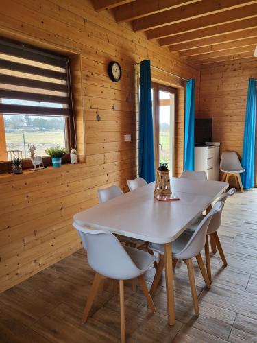 a dining room with a white table and chairs at Słowińskie Widoki domki Flora, Fauna, noclegi Smołdziński Las in Smołdziński Las