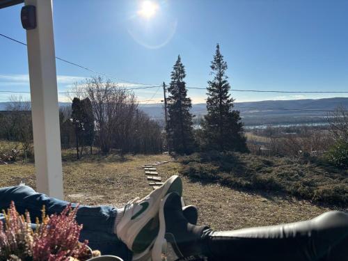 a person sitting on a porch with their feet up on the porch at Szarvas Vendégház in Zebegény