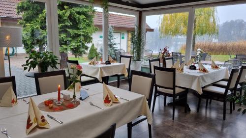 a restaurant with white tables and chairs and windows at Haus Katharinensee in Müllrose