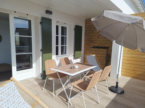 a table and chairs with an umbrella on a porch at Les iles, T2 vue mer in Rivedoux-Plage