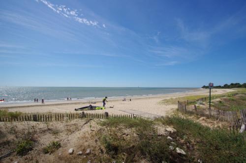 a group of people walking on a beach at La Terrasse, studio vue mer in Rivedoux-Plage