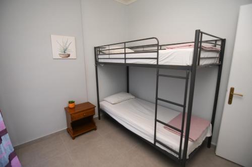 a bunk bed room with two bunk beds and a table at Rose Garden Apartments in Mitikas