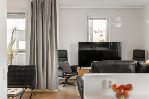 a living room with black leather furniture and a flat screen tv at Come in! "Ilmatar" Luxury apartments in the heart of Tampere with yacuzzi option! in Tampere