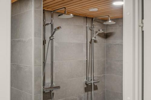 a shower stall in a bathroom with gray tiles at Come in! "Ilmatar" Luxury apartments in the heart of Tampere with yacuzzi option! in Tampere