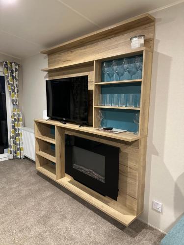 a entertainment center with a television and a fireplace at Silver Dunes in Lossiemouth