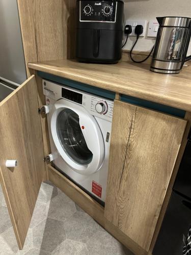 a washing machine in a kitchen under a counter at Silver Dunes in Lossiemouth