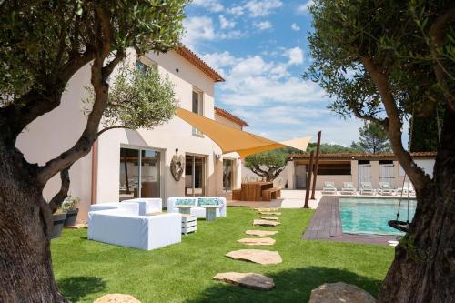 un jardin avec des meubles blancs et une piscine dans l'établissement Villa d'exception avec piscine - Le Mas des Filles, à Solliès-Pont