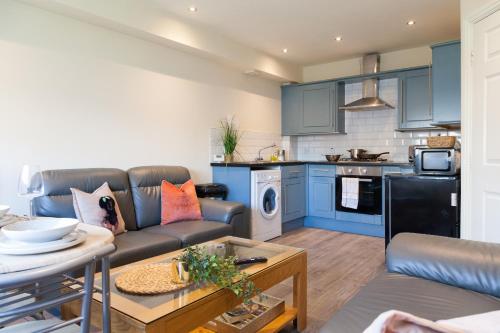 a living room with a couch and a kitchen at Pinfold Court Apartments in Knowsley