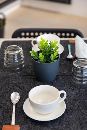 a table with plates and a plant in a pot at Dea's Rooms in Noto