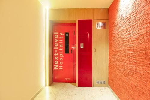 a hallway with a red door and a brick wall at FabHotel Nestlay Rooms High Court - Nr Parry's Corner in Chennai