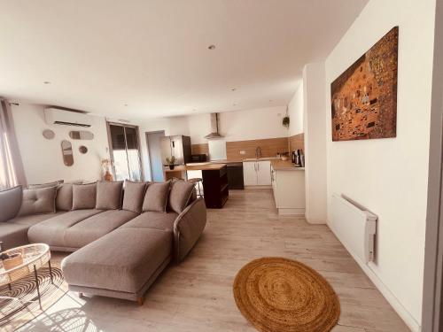 Il comprend un salon avec un grand canapé et une cuisine. dans l'établissement Le Félicité appartement spacieux avec parking, à Nîmes