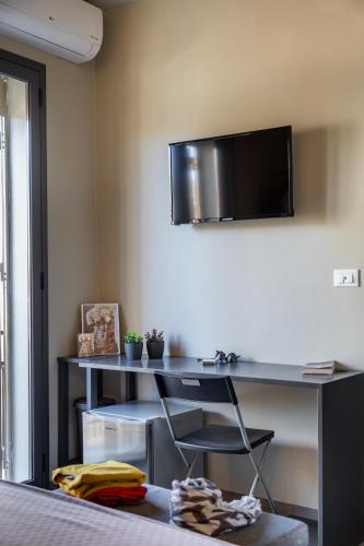 a room with a desk with a television on the wall at Dea's Rooms in Noto