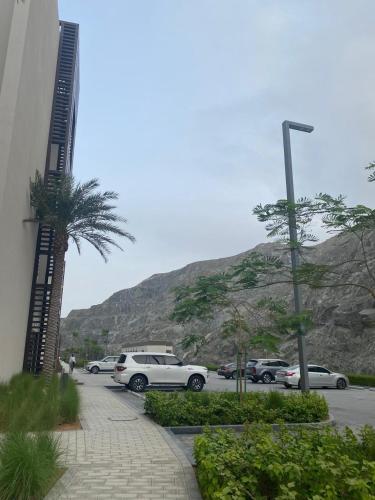 a parking lot with cars parked next to a mountain at Address beach resort Fujairah Apartment in Fujairah