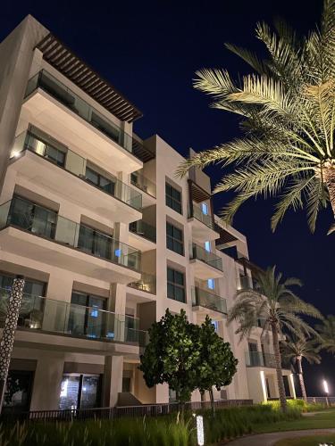 a large white building with palm trees in front of it at Address beach resort Fujairah Apartment in Fujairah
