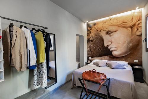 a bedroom with a bed and a large painting of a woman at Dea's Rooms in Noto