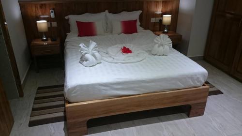 a large bed with white sheets and decorations on it at MC Self Catering in Baie Sainte Anne