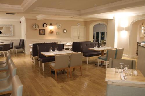 a restaurant with tables and chairs in a room at Leighinmohr House Hotel in Ballymena