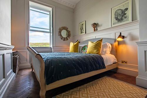 巴斯Exquisite grandeur - Central Bath的一间卧室，有一张带黄色枕头的床和一扇窗户
