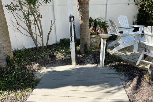 a porch with two chairs and a table and a tree at Georgianne Suite Two in Tybee Island