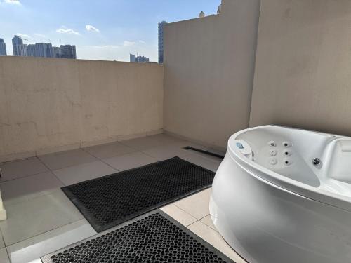 a white bath tub in a bathroom with a view at 1BR Apartment with Private Jacuzzi in JVC - JLiving in Dubai