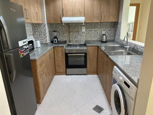 a kitchen with a stainless steel refrigerator and a dishwasher at 1BR Apartment with Private Jacuzzi in JVC - JLiving in Dubai