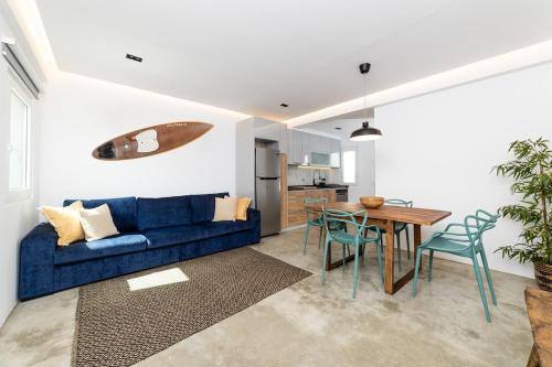 a living room with a blue couch and a table at Sunset House - by Monte das Alpenduradas in Zambujeira do Mar