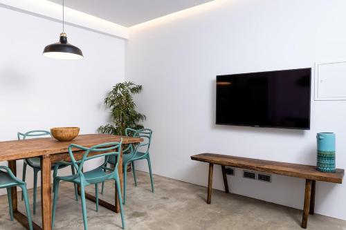 a dining room with a table and chairs and a flat screen tv at Sunset House - by Monte das Alpenduradas in Zambujeira do Mar