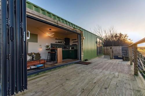 a green building with a large window on a deck at Contemporary Container with hot tub in Bath