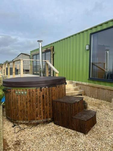 a green building with a hot tub and two benches at Contemporary Container with hot tub in Bath