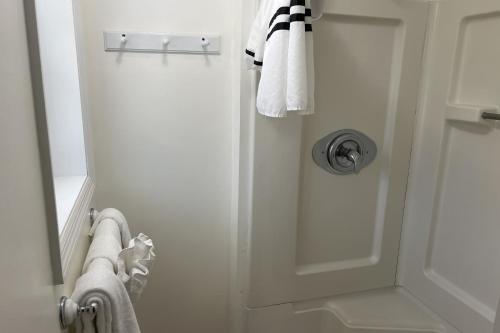 a bathroom with a shower with a door and towels at Georgianne Suite Eight in Tybee Island