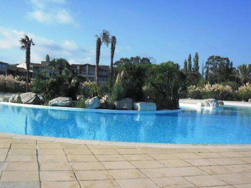 une grande piscine avec des palmiers en arrière-plan dans l'établissement Gasjoly - Golfe de St-Tropez Studio avec cabine climatisé pour 4 personnes, à Gassin