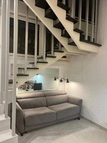 - un salon avec un canapé sous un escalier dans l'établissement L'Architek, à La Grande Motte