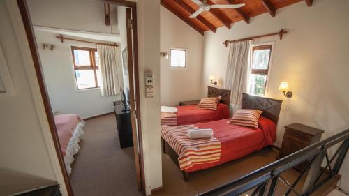 a bedroom with two beds with red sheets and a balcony at Costa Remanso in Miramar