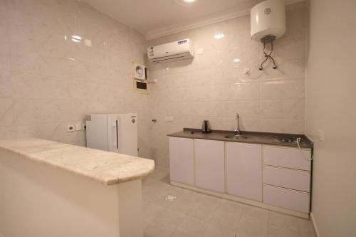 a white kitchen with a sink and a refrigerator at شقق المصيف للشقق المخدومة in Abha
