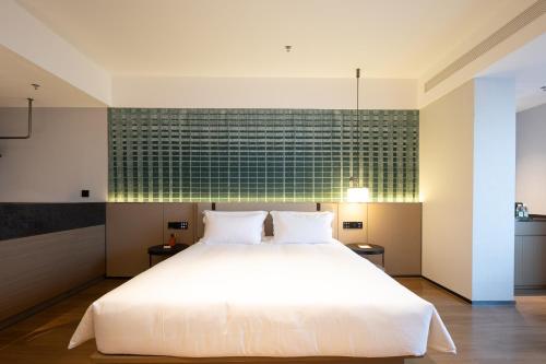 a bedroom with a white bed and a green wall at Liangzhi Huipin Hotel Haikou West Coast Yongwan Road Branch in Haikou