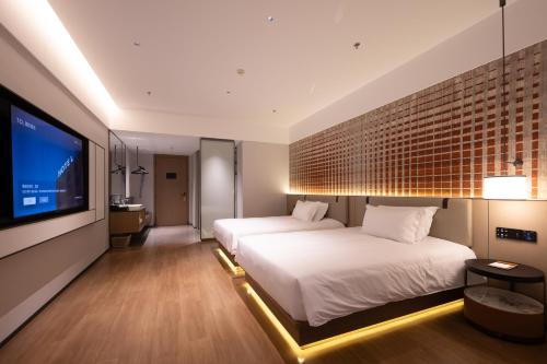 a bedroom with two beds and a flat screen tv at Liangzhi Huipin Hotel Haikou West Coast Yongwan Road Branch in Haikou