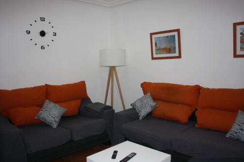 a living room with two couches and a clock on the wall at Una ciudad por descubrir in Valencia de Don Juan