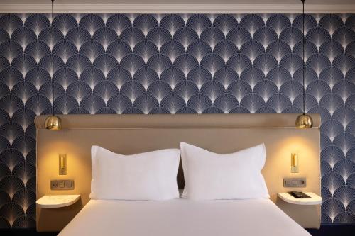 a bedroom with a large bed with white pillows at Hotel The Augustin in Brussels