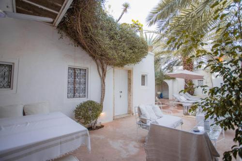 a bedroom with a bed and chairs and a patio at La Maison Blanche -Les Houchs De Djerba in Erriadh