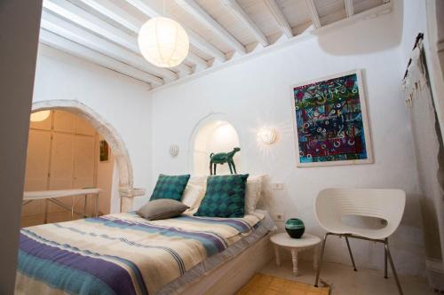 a small bedroom with a bed and a chair at La Maison Blanche -Les Houchs De Djerba in Erriadh