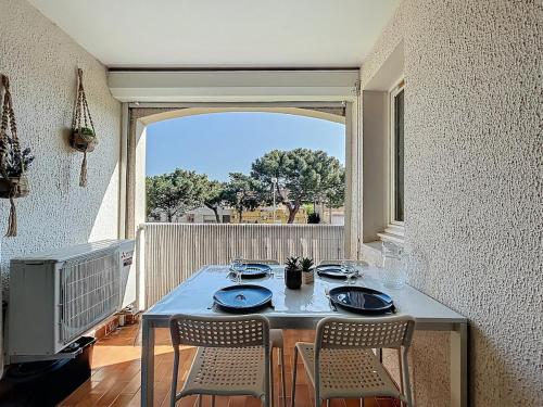 une table avec quatre chaises dans une chambre avec fenêtre dans l'établissement 3670-Appartement à 400m des plages, à Argelès-sur-Mer