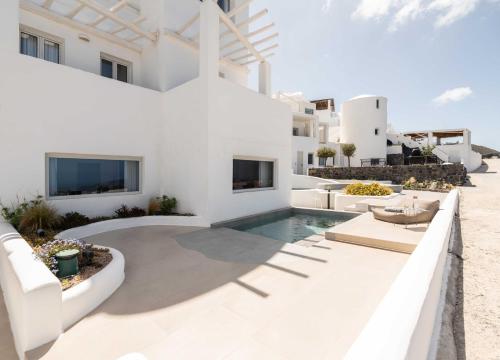 a white villa with a swimming pool and a resort at Rocabella Santorini Hotel & Spa in Imerovigli