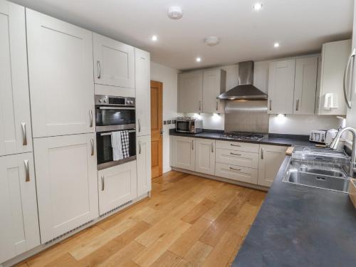 a kitchen with white cabinets and a wooden floor at 4 Centurion Rise in Penrith