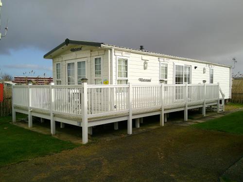 a white house with a porch and a fence at The Wolds Westwood 6 Berth, Central Heated in Ingoldmells