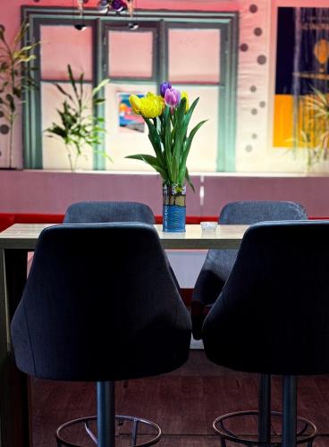 a table with two chairs and a vase of flowers at Mouse House in Chişinău