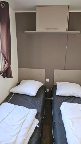 deux lits dans une petite pièce avec des draps blancs dans l'établissement Joli Mobil home N137, 4ch tout confort et spacieux, à Gastes