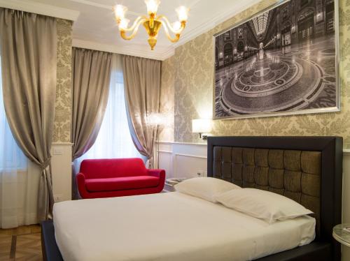 a bedroom with a bed and a red chair at Duomo Rooms in Milan